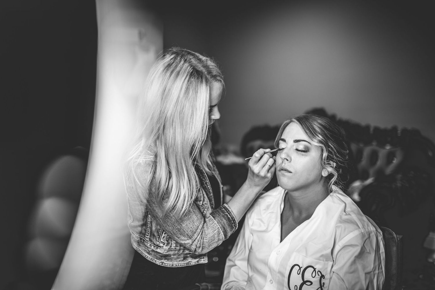A black and white image showing makeup application preparation before a wedding ceremony.