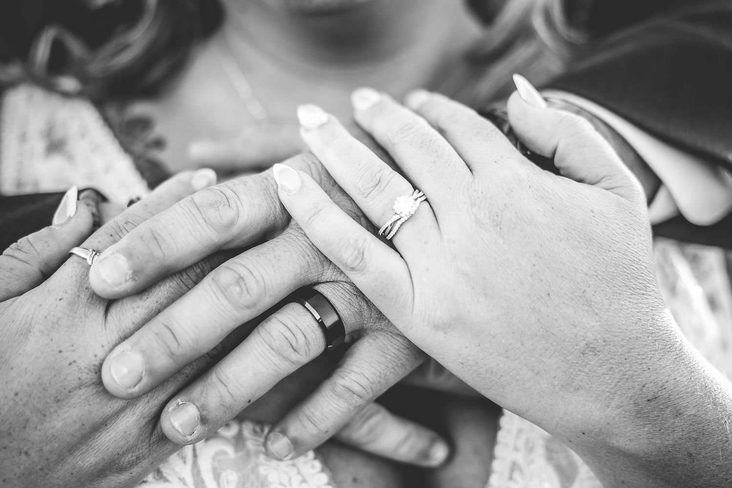 Black and white close-up of hands touching with wedding rings in an intimate moment.