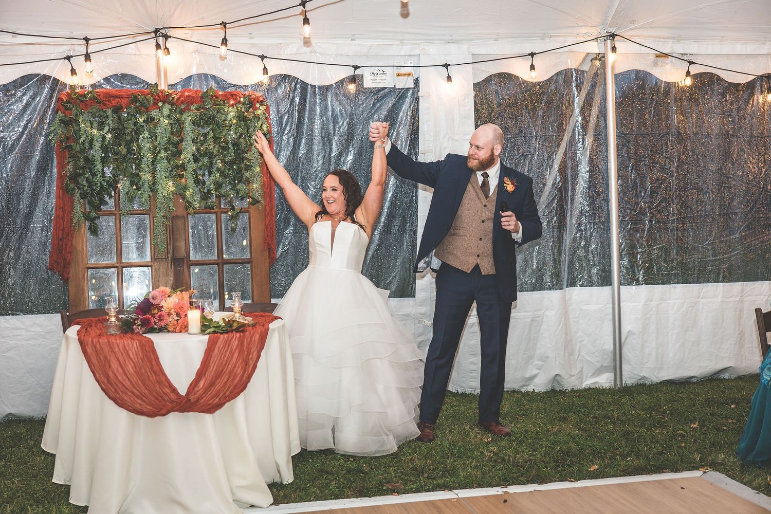 Outdoor wedding tent with string lights and white drapes creating magical atmosphere.