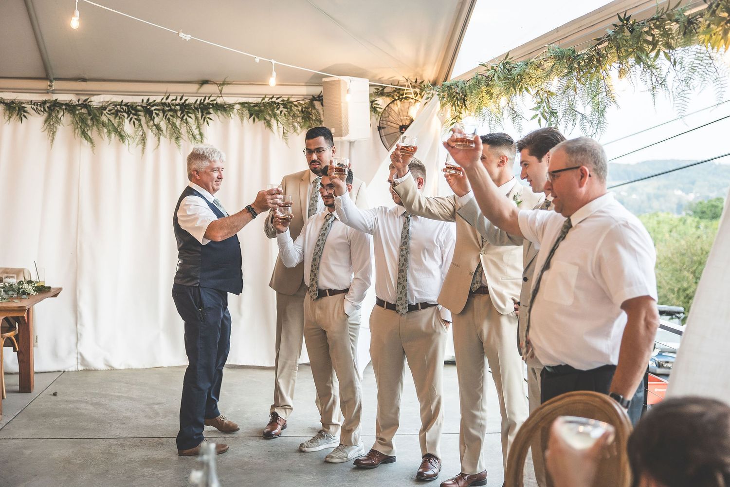 Wedding party members in light colored attire celebrate together during a reception.