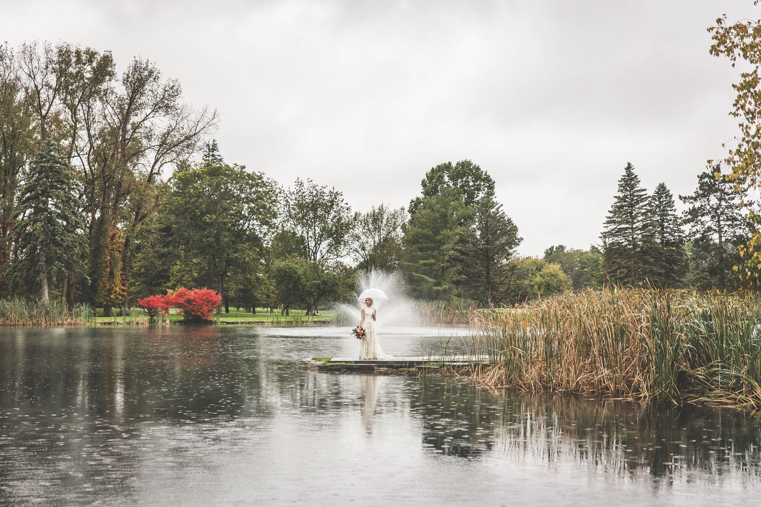 Panoramic view of a misty lake with stone pathways and autumn foliage.