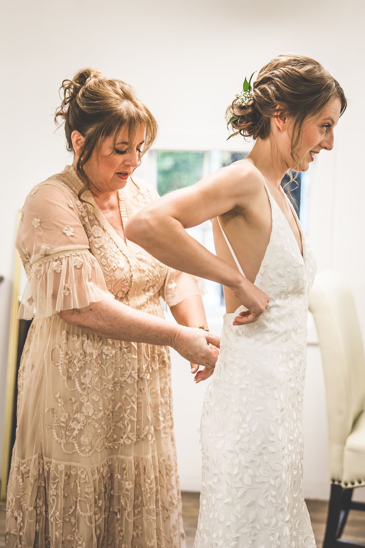 Two people in elegant dresses share an intimate moment while getting ready for a special occasion.