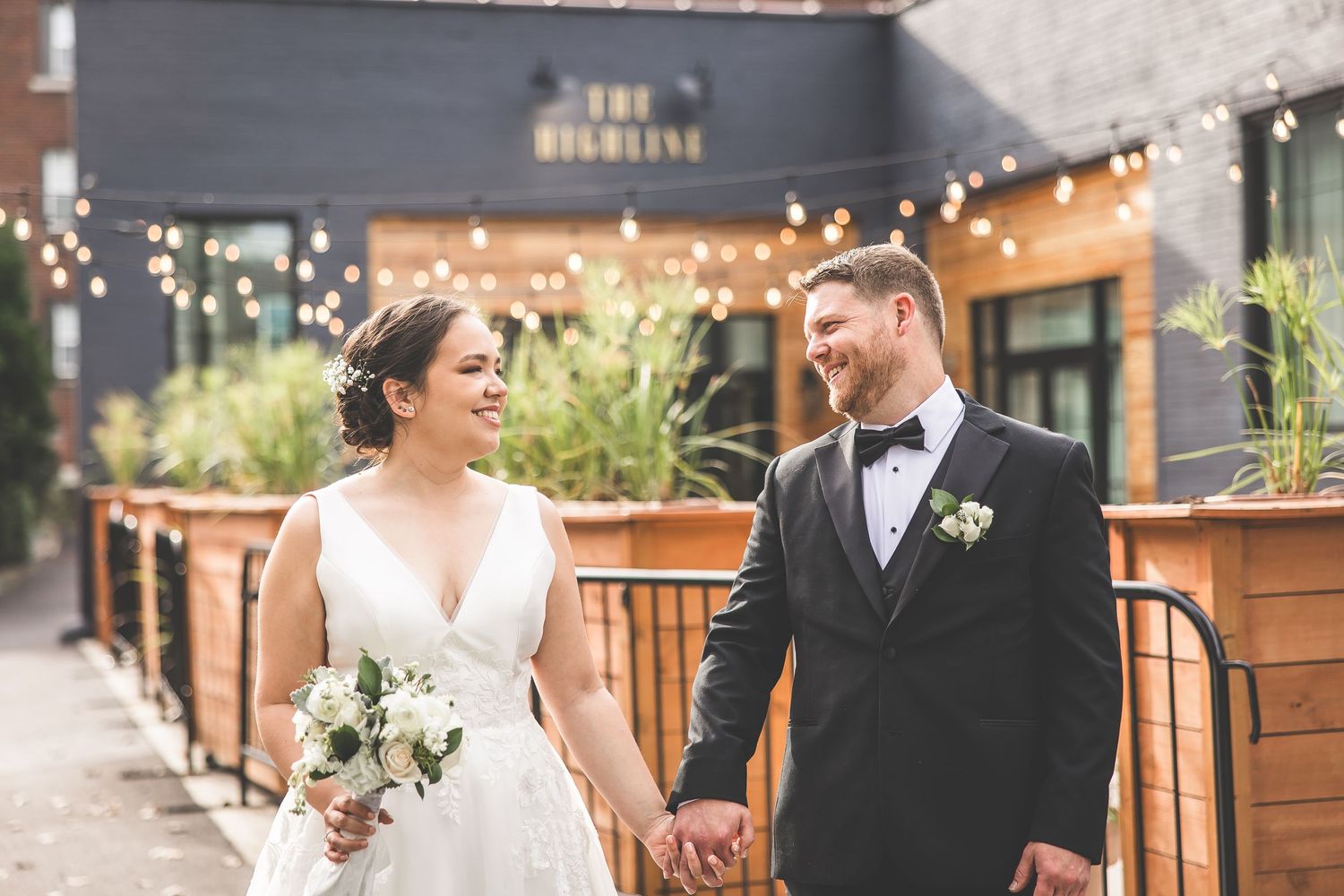 Romantic wedding portraits captured at an urban venue with string lights and wooden details.