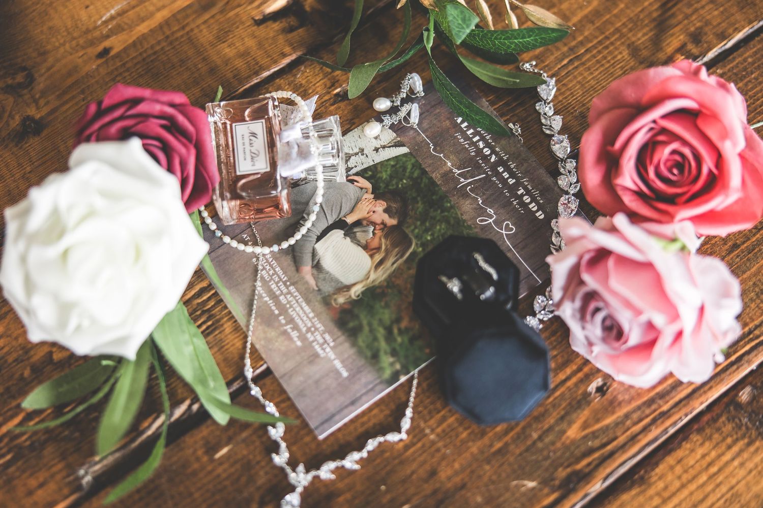 Pink and white roses with decorative elements arranged on a rustic wooden surface for a wedding celebration.