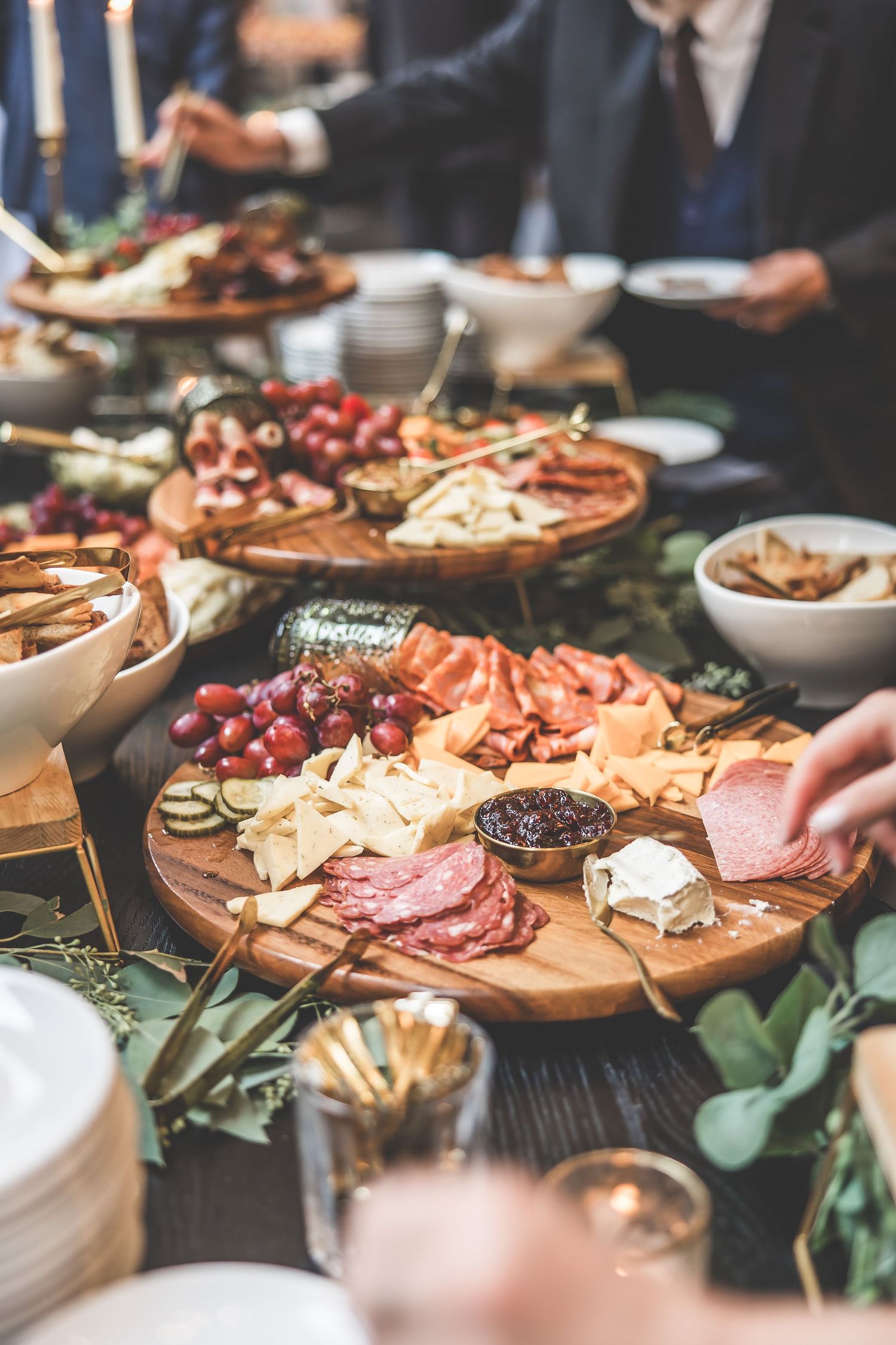 Elegant charcuterie board with meats, cheeses, and grapes arranged on wooden platter at wedding reception.