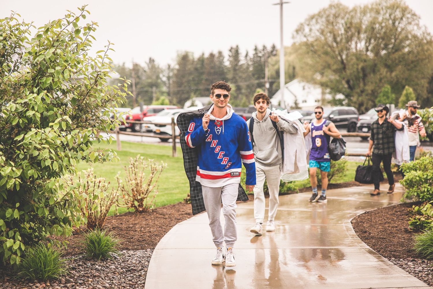 Group walking along pathway wearing sports team apparel on overcast day.