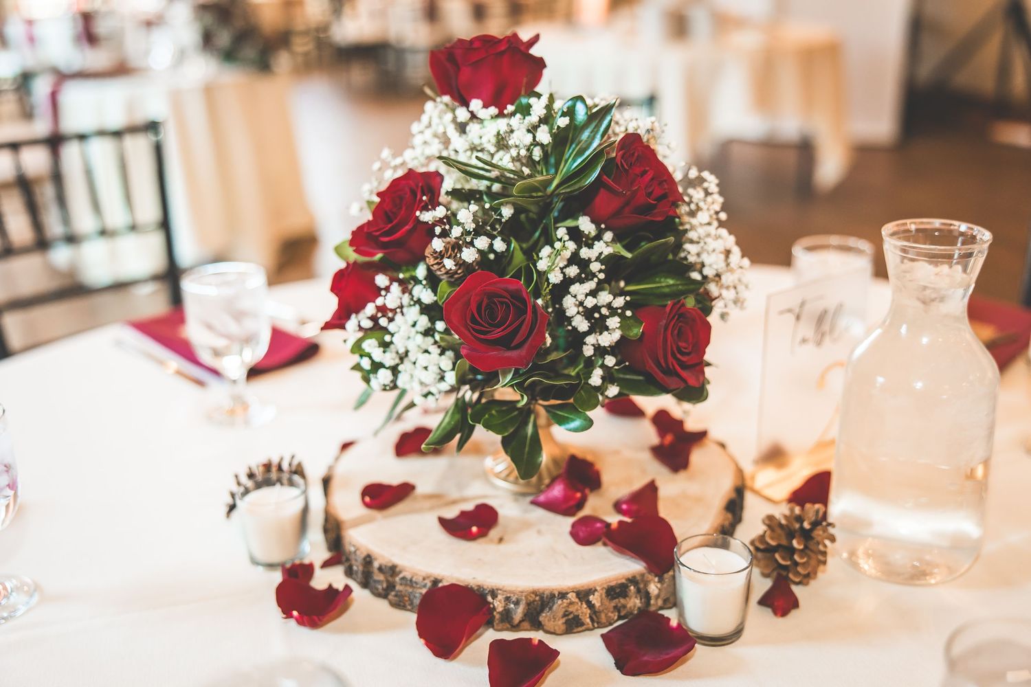 Elegant wedding reception tables decorated with red roses, white flowers and romantic candlelight.