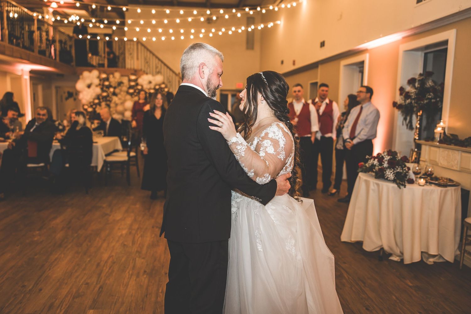Wedding reception venue decorated with string lights and white tablecloths creating a romantic atmosphere.