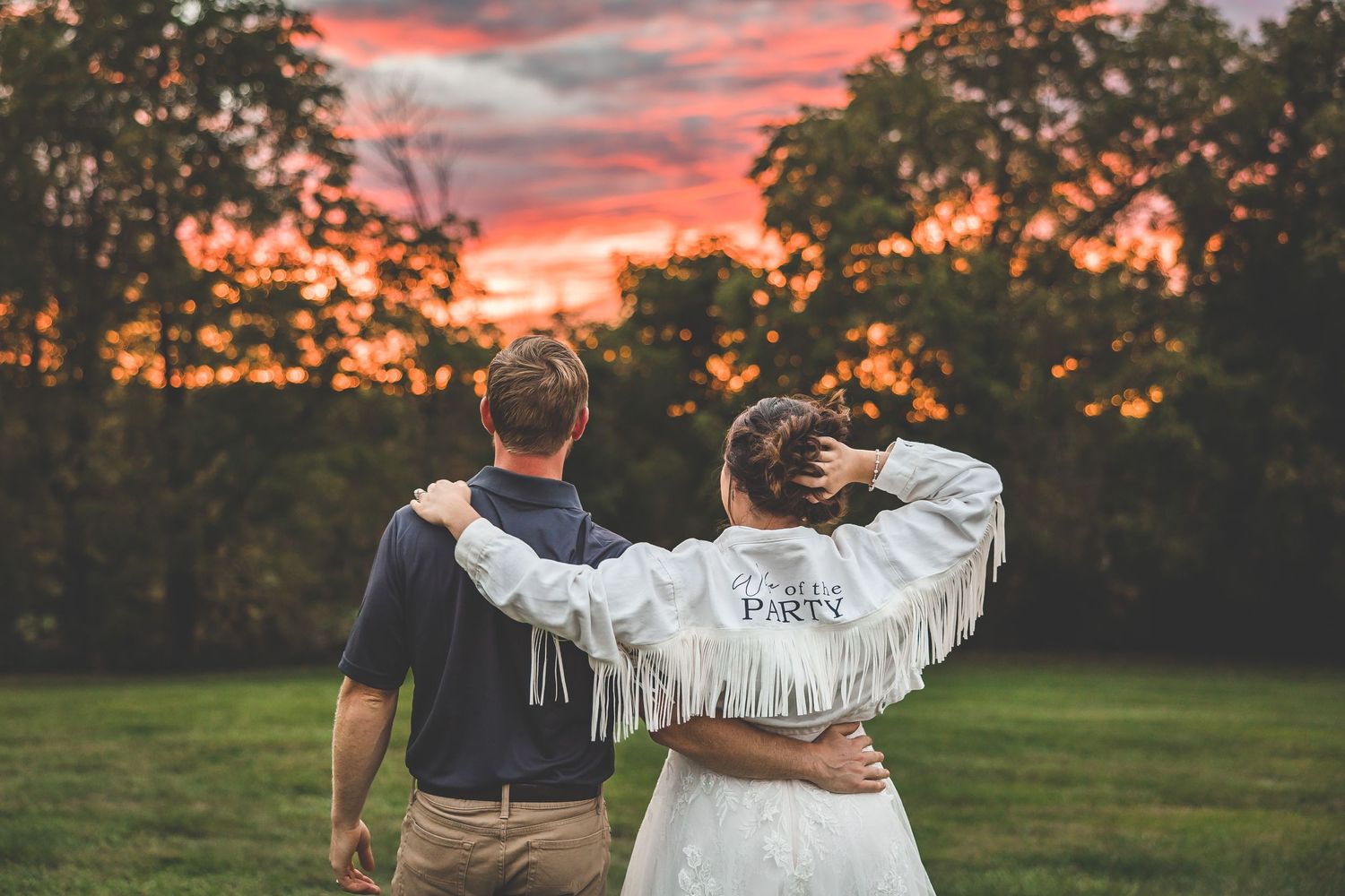 Silhouettes against a dramatic sunset sky during outdoor wedding portraits.