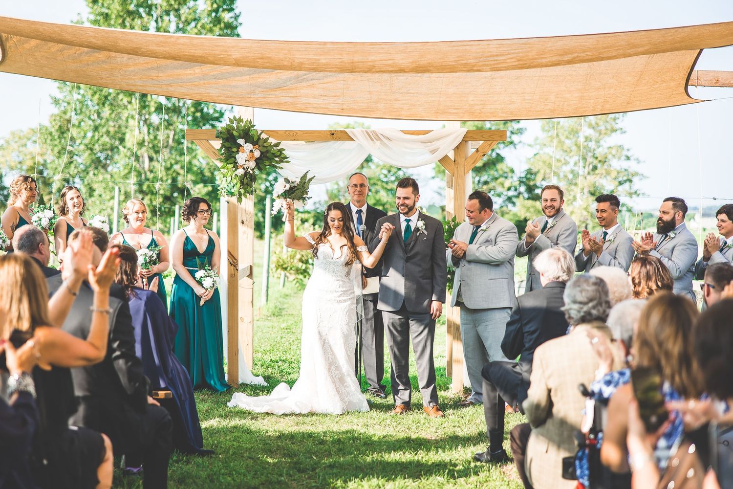 Wedding party and family members posing outdoors with autumn trees in background.