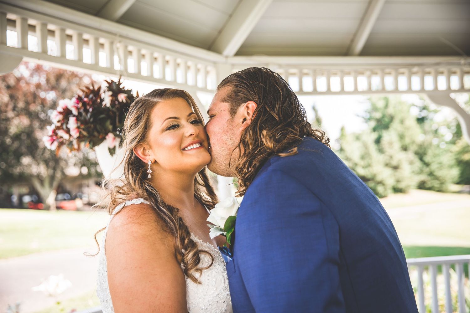 Couple dancing and laughing together under white gazebo during wedding celebration.