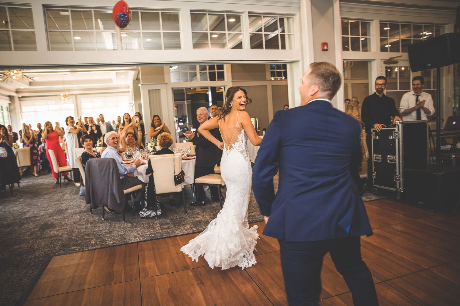 Wedding guests dancing and celebrating in a spacious reception hall.