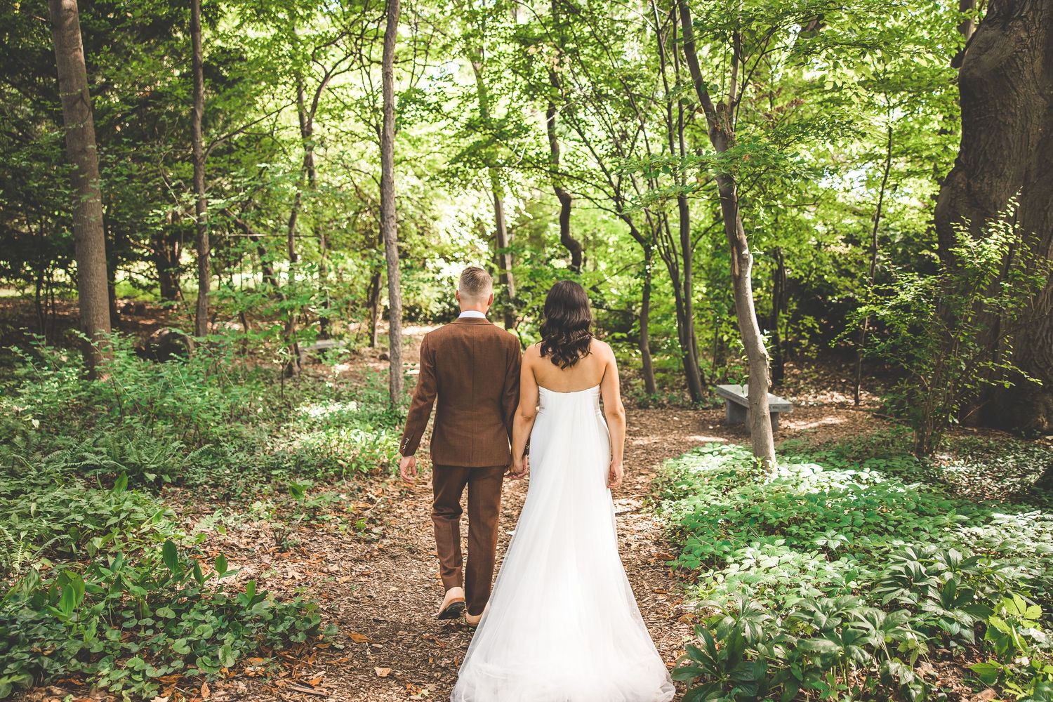 Couple shares candid moments during their woodland wedding photoshoot surrounded by trees.