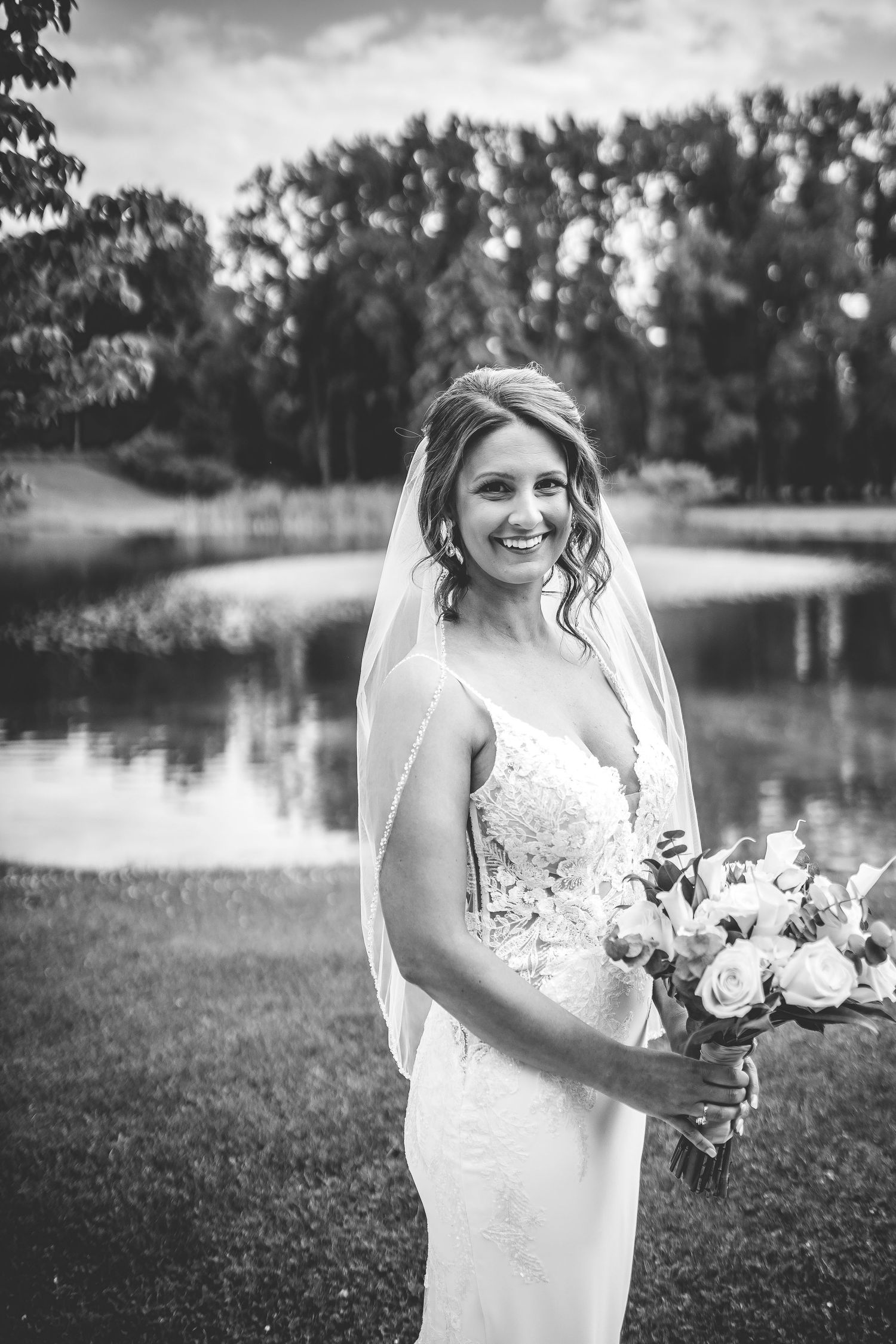 Black and white wedding photography by a lake with natural scenery.