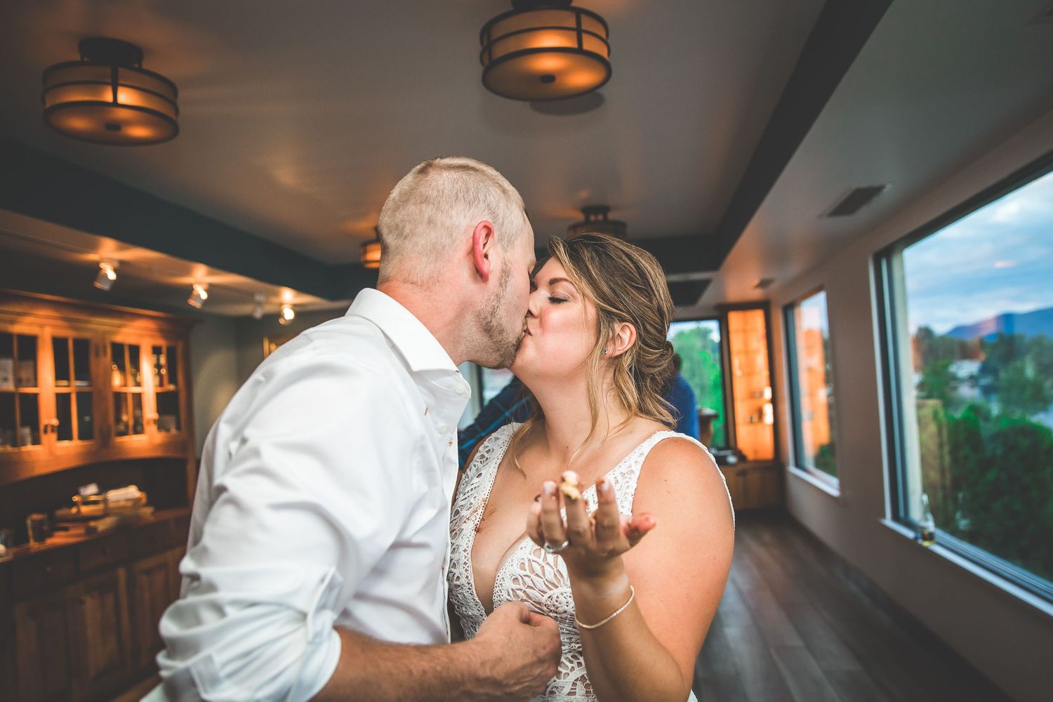 Couple sharing romantic dance moment under atmospheric lighting at indoor wedding venue.