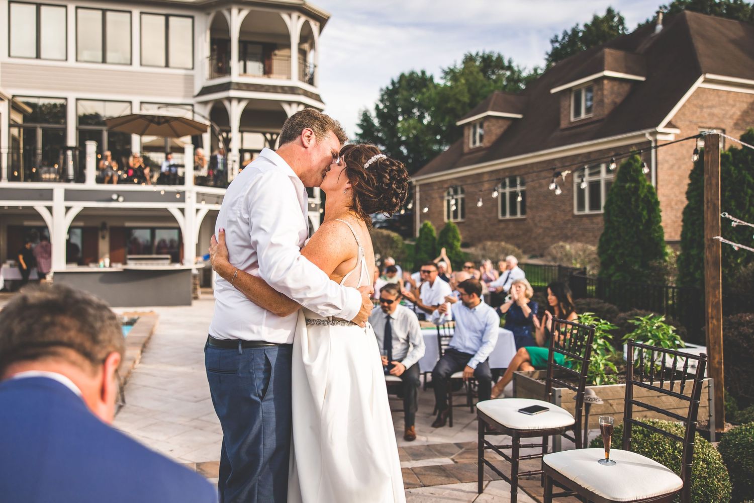 A couple shares their first dance on an outdoor terrace with guests watching.