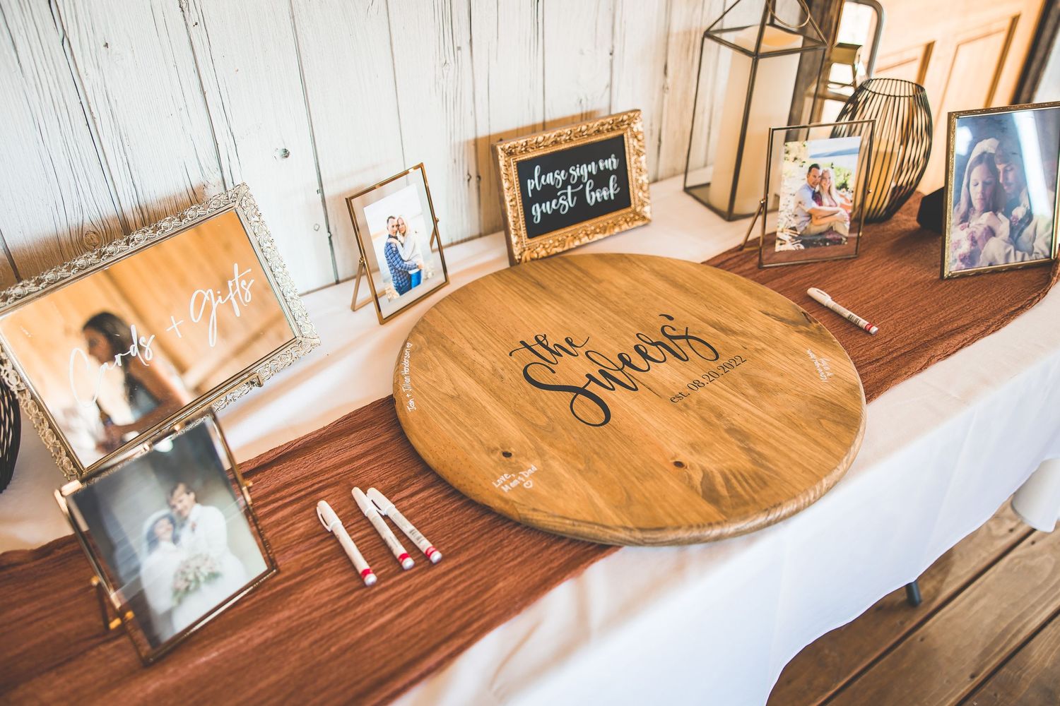 Wedding guest book table with wooden decor and framed photos.