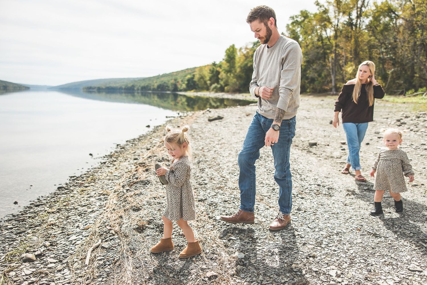 Family walking and playing together on a rocky lakeside beach.