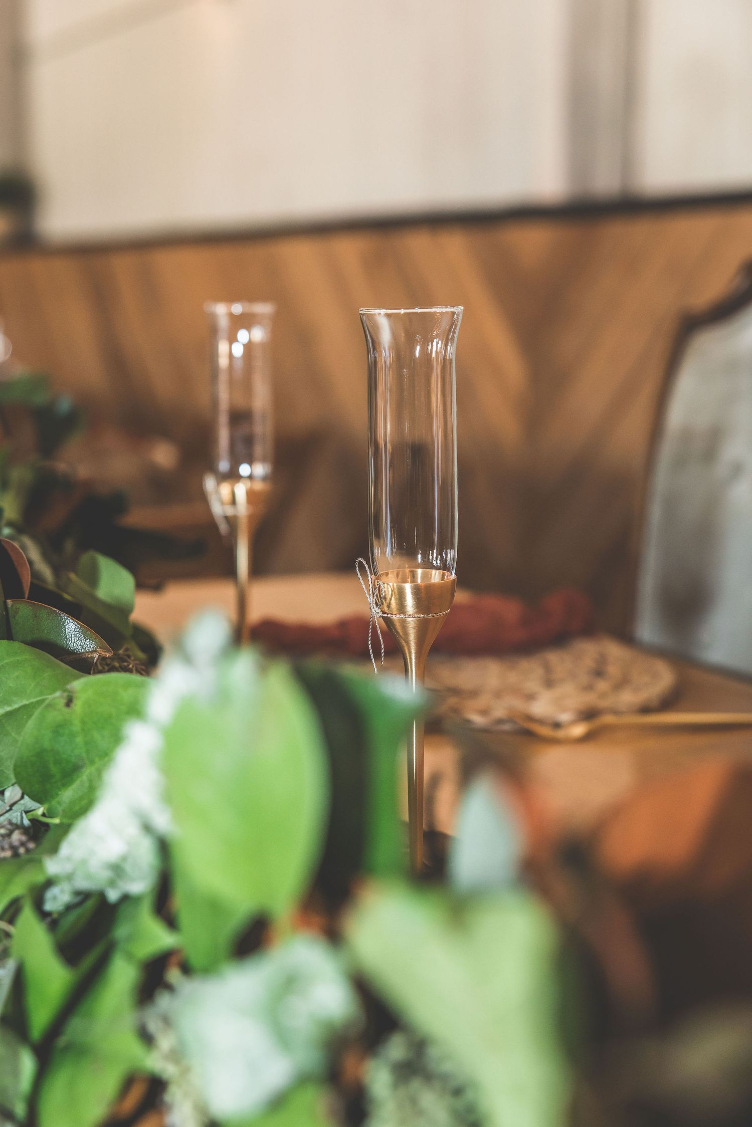 Close-up of champagne flutes and greenery decorations at an event setting.