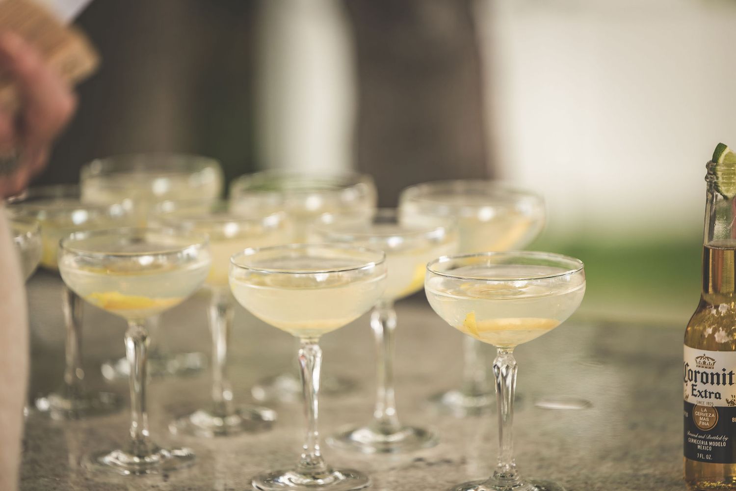 Rows of champagne glasses arranged on a rustic table at an outdoor event.