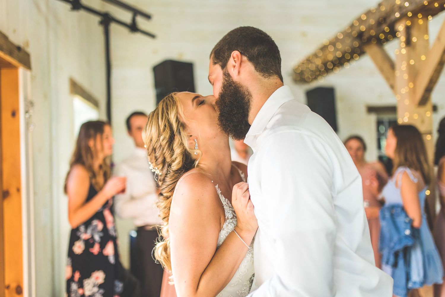 Wedding reception dance floor filled with guests celebrating under string lights.