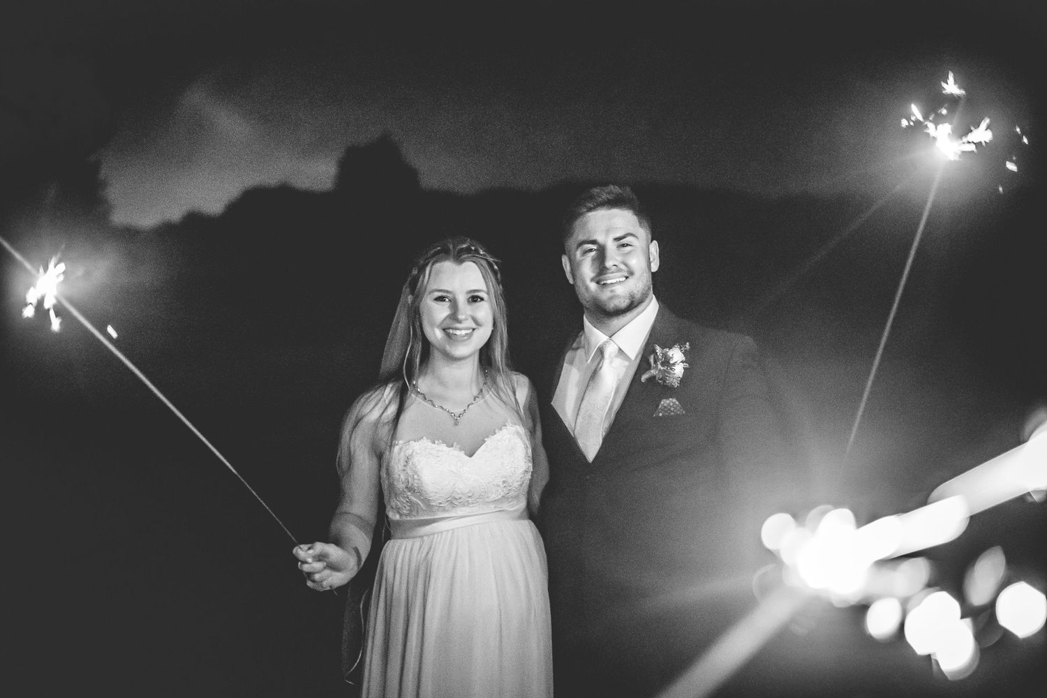 Wedding guests dance under twinkling lights during an outdoor nighttime celebration.