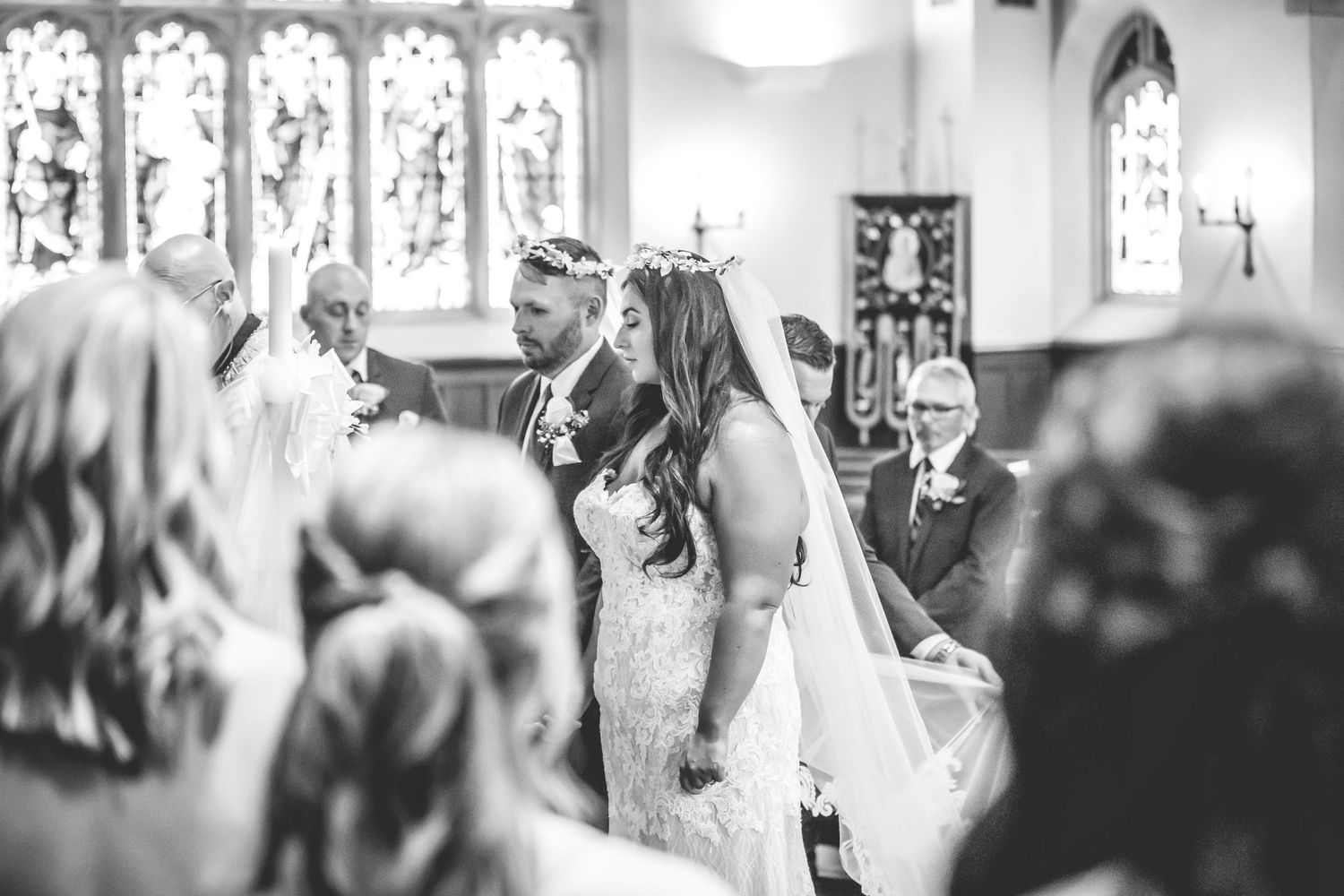 Candid black and white photograph showing wedding guests in a historic church setting.