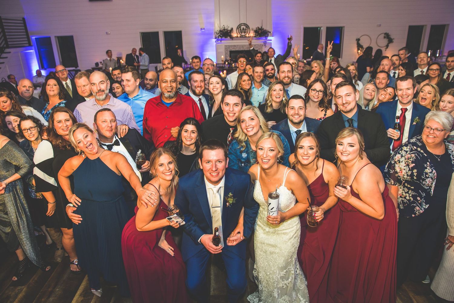 Large group photo of wedding party and guests at reception venue.