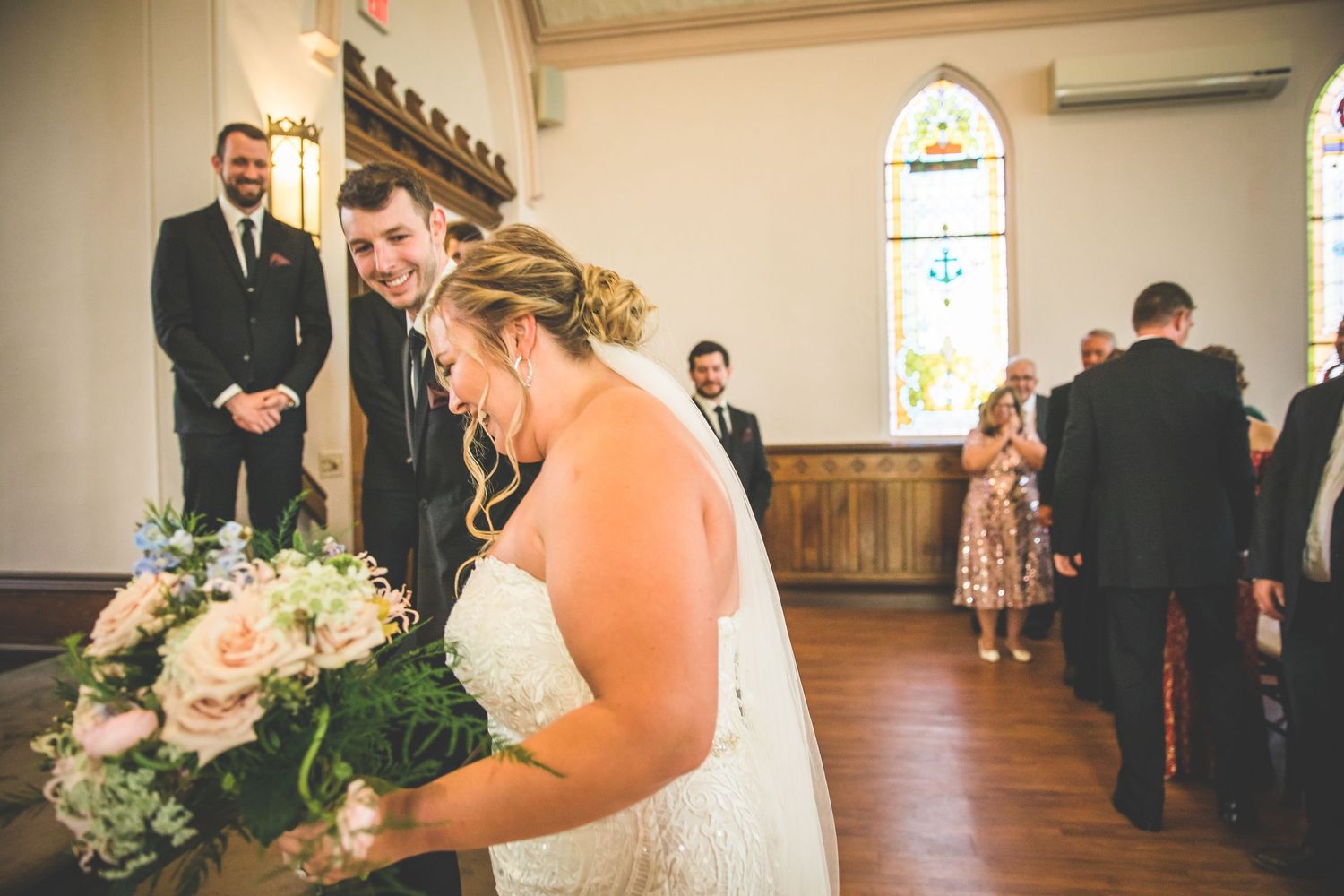 Wedding ceremony in progress inside a historic church with wooden floors.