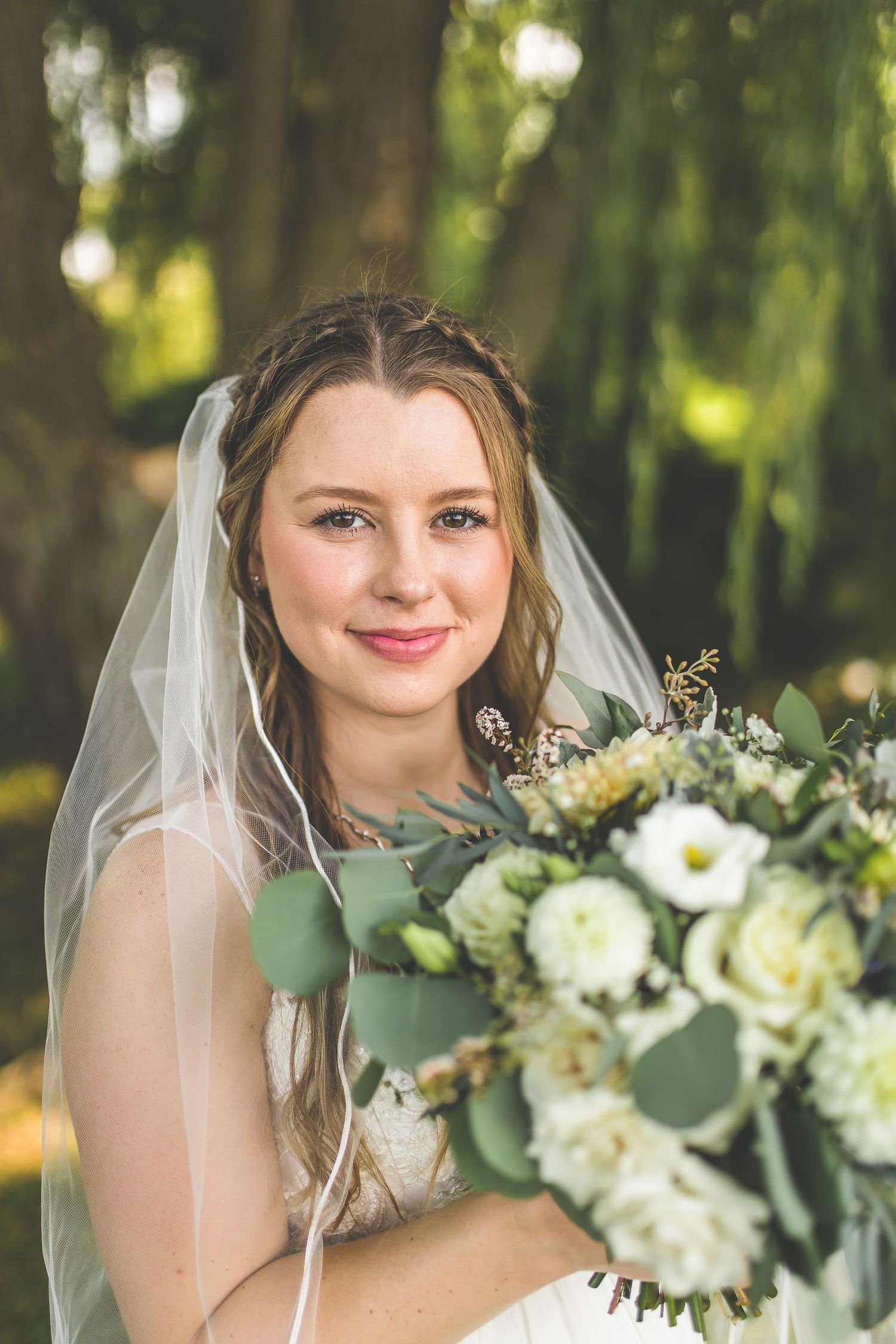 Close up of white and green bridal bouquet with eucalyptus leaves and delicate flowers.