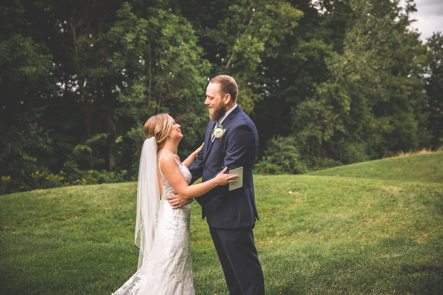 Wedding couple reacts with joy during their first look in a natural outdoor setting.
