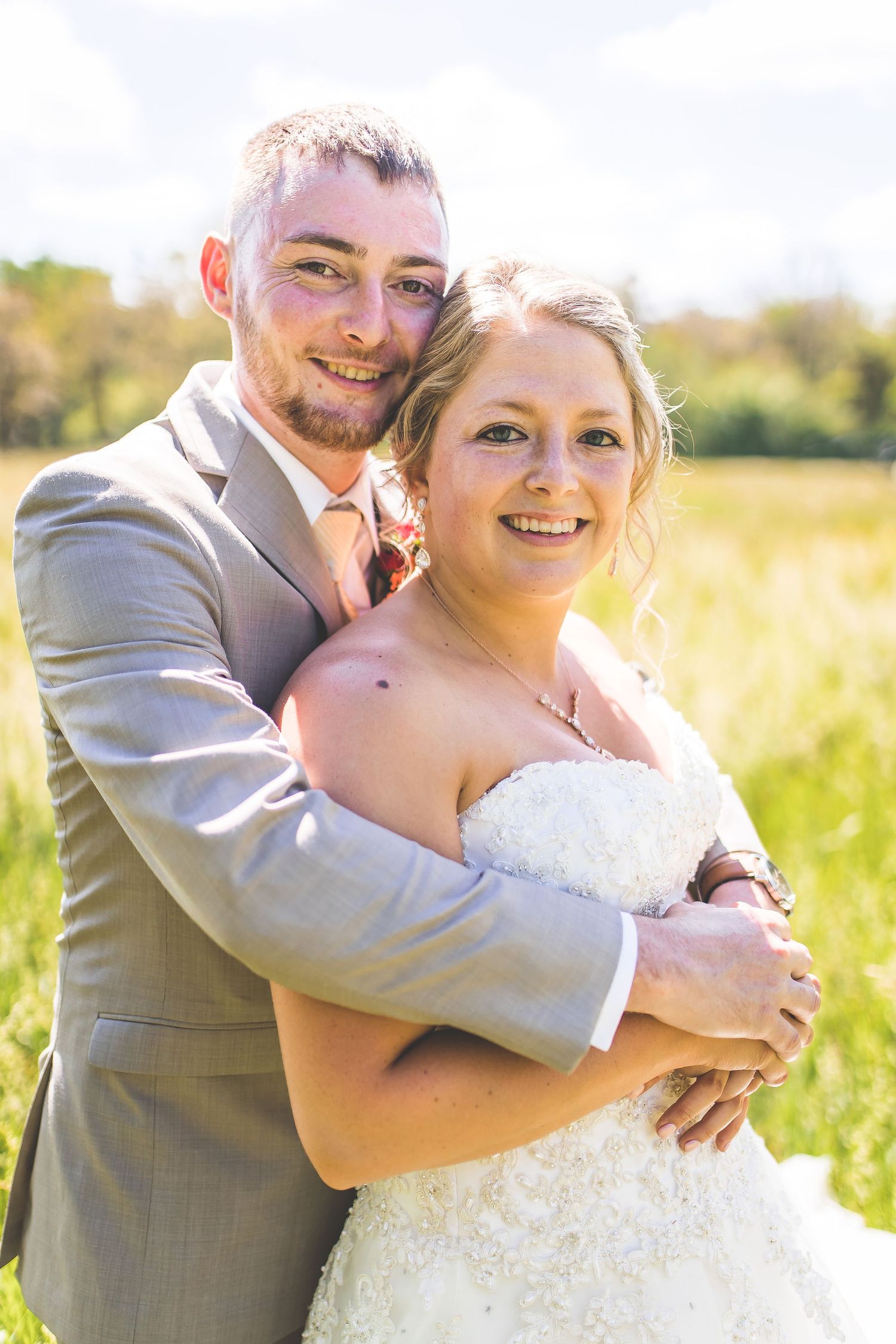 Romantic wedding portraits captured in a sunny field with warm golden light.