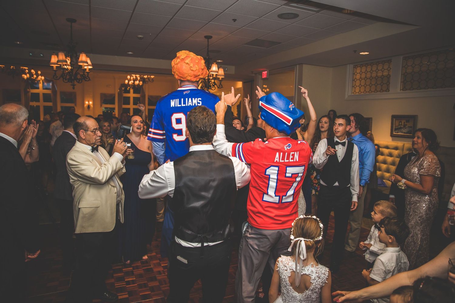Wedding guests wearing sports jerseys celebrating on the dance floor.