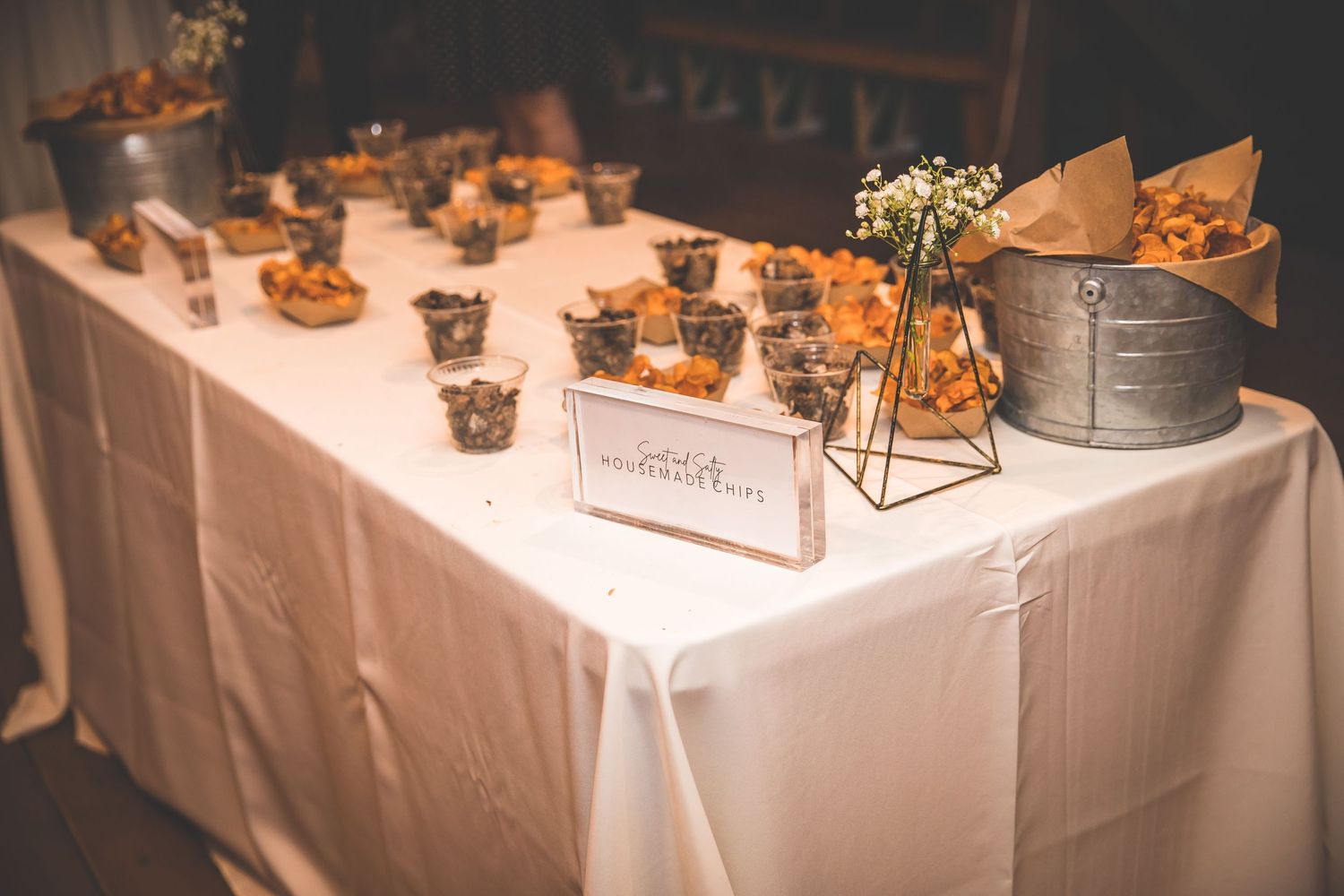 Elegant dessert and appetizer table display with white linens and decorative arrangements at a wedding reception.