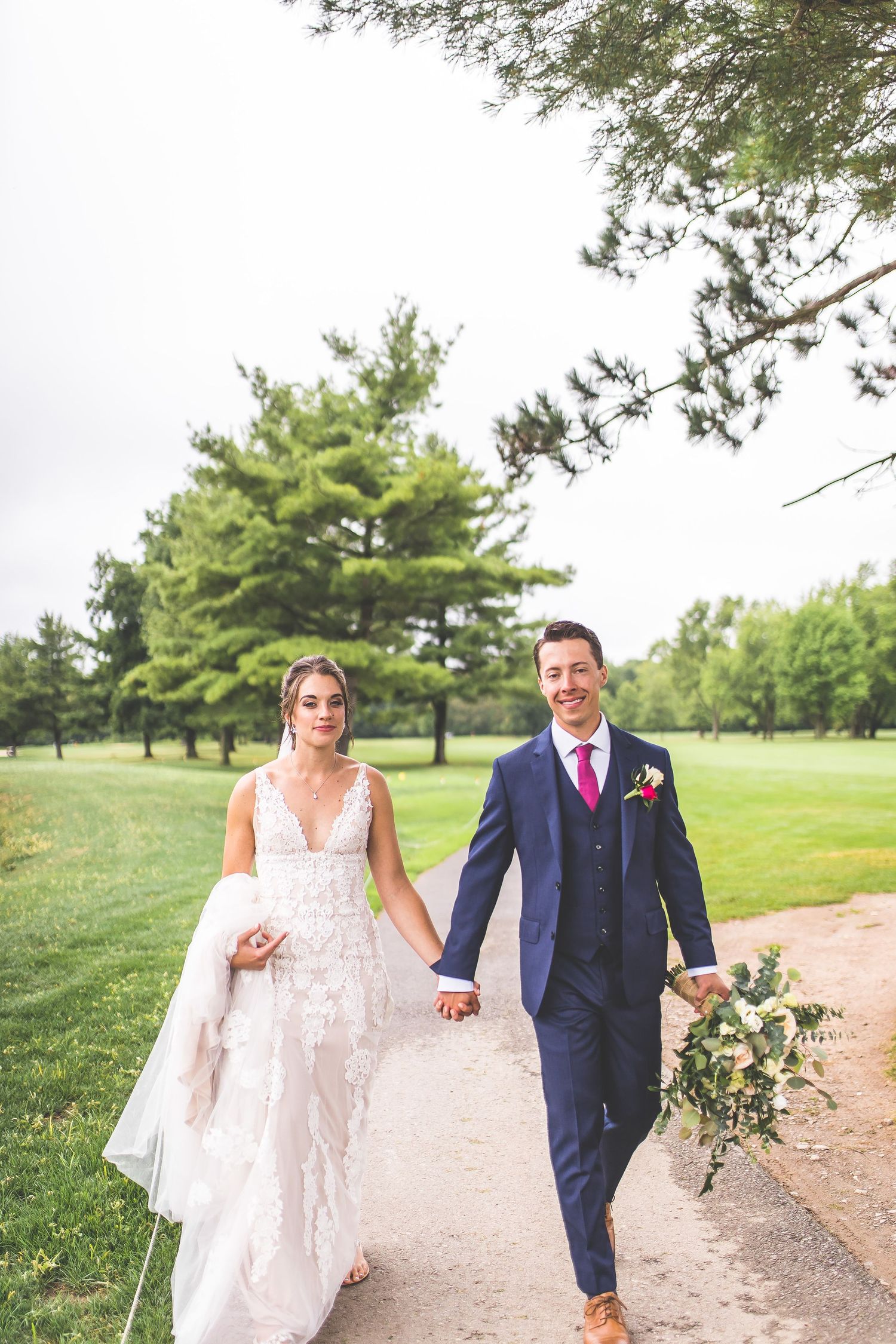 Couple strolls along a winding path in a scenic garden setting during their wedding photoshoot.