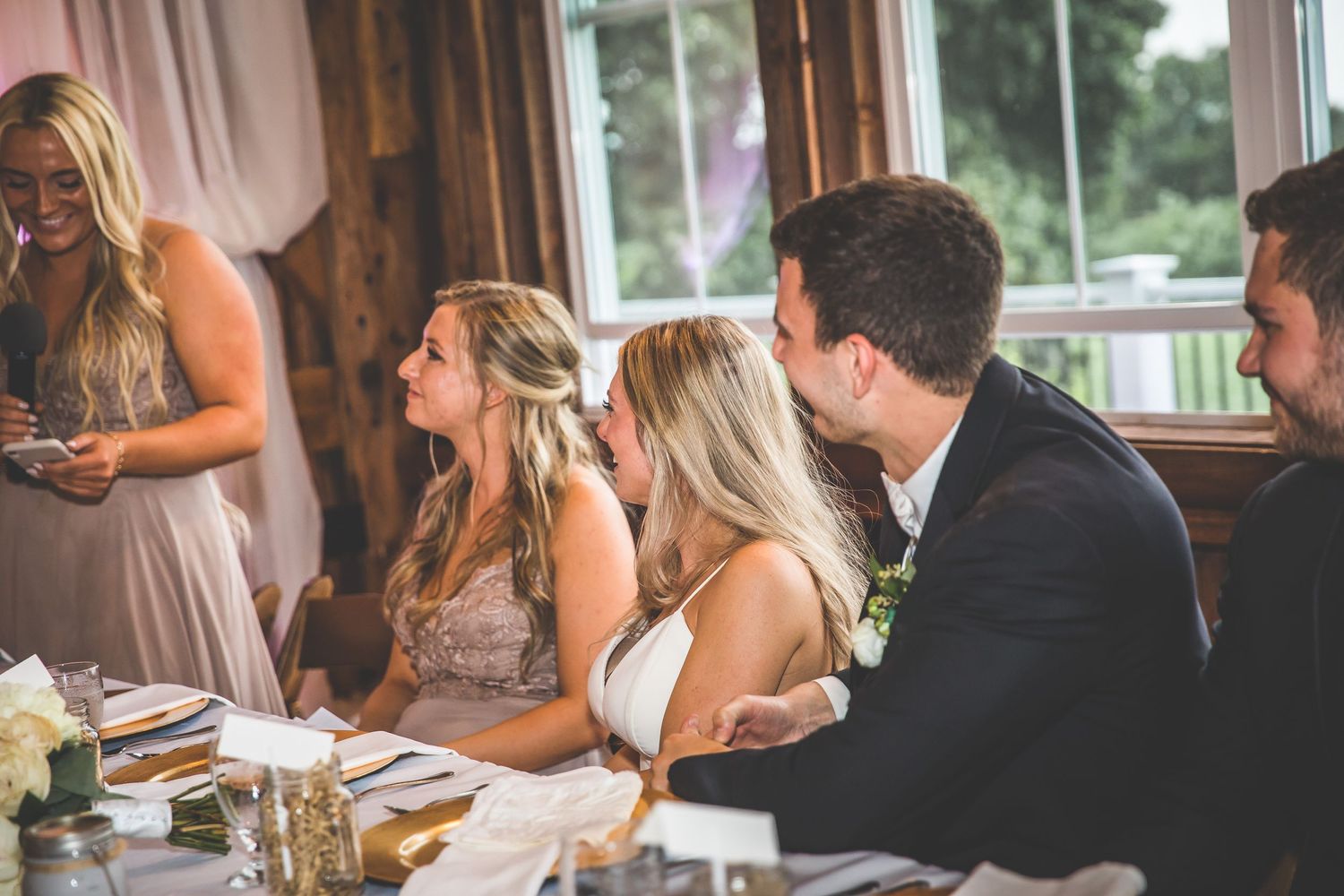 Wedding reception guests listen attentively during dinner speeches at decorated venue.