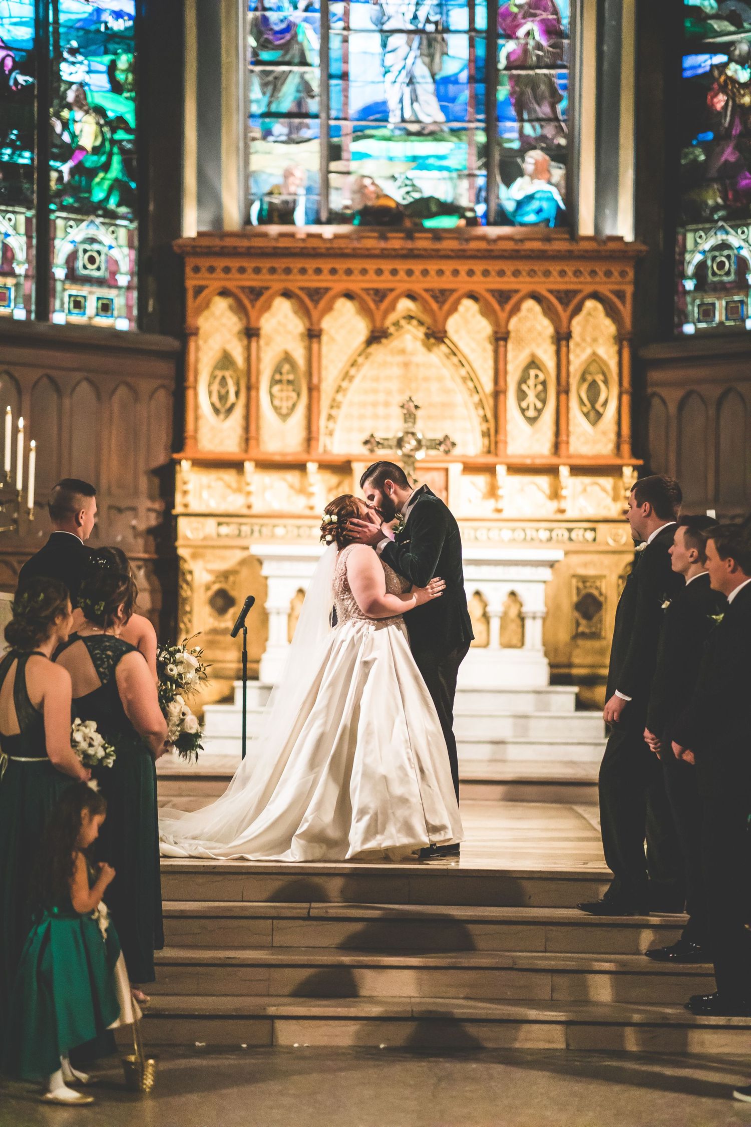Wedding ceremony in church with stained glass windows and ornate altar.