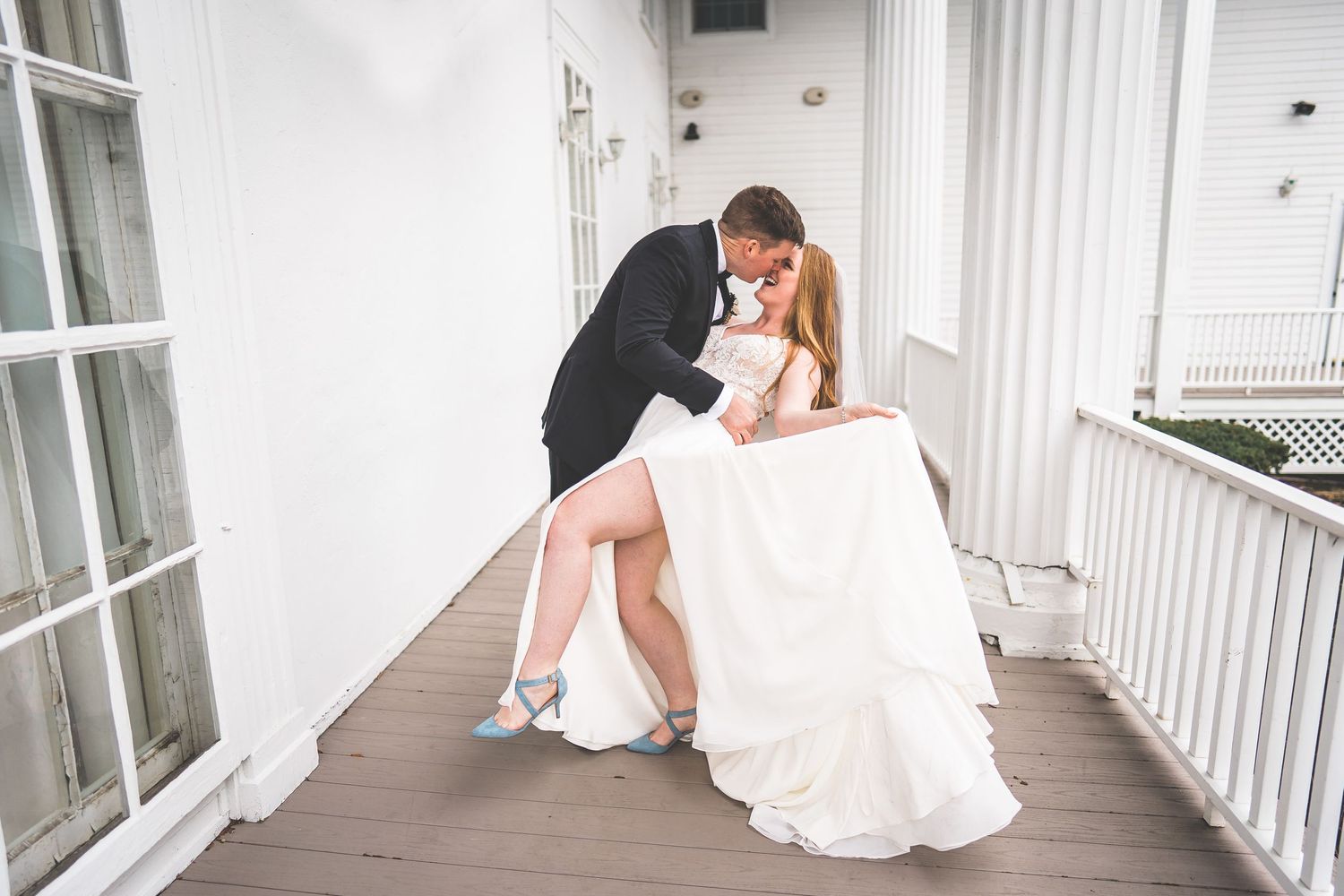 Candid wedding moments captured on white columned porch in natural light.