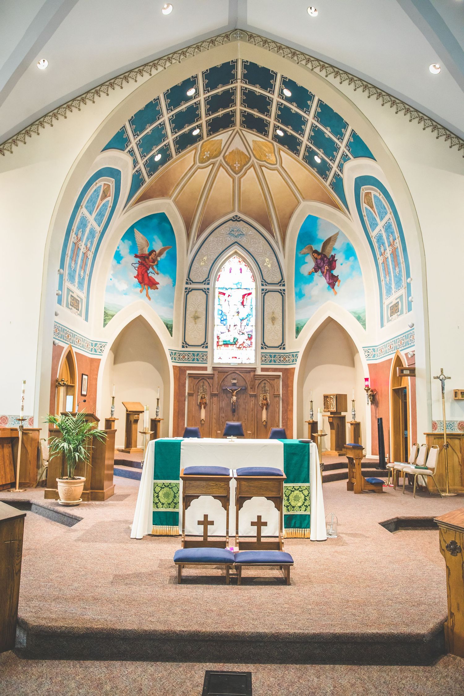 Interior of a church sanctuary with beautiful blue vaulted ceiling and stained glass windows.