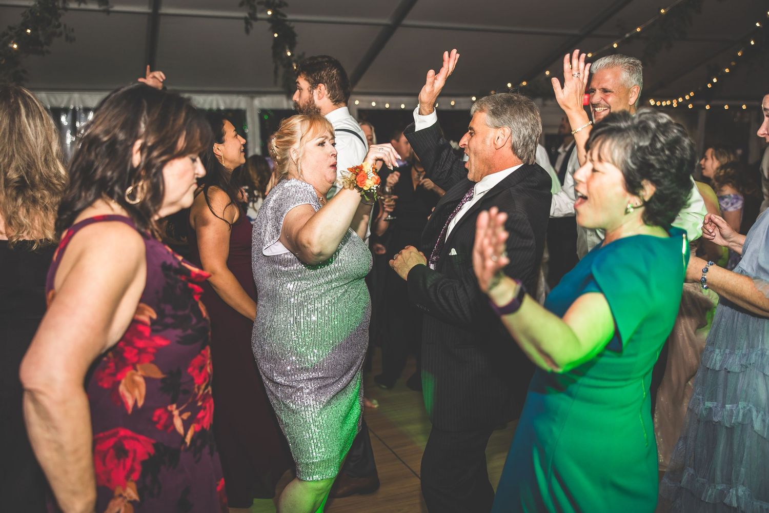 Energetic dancers in colorful dresses enjoying themselves at a wedding reception.