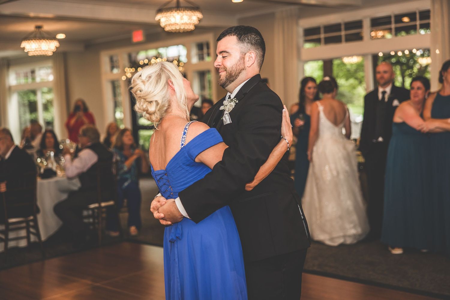 Guests dance and celebrate at an elegant wedding reception with blue accent lighting.