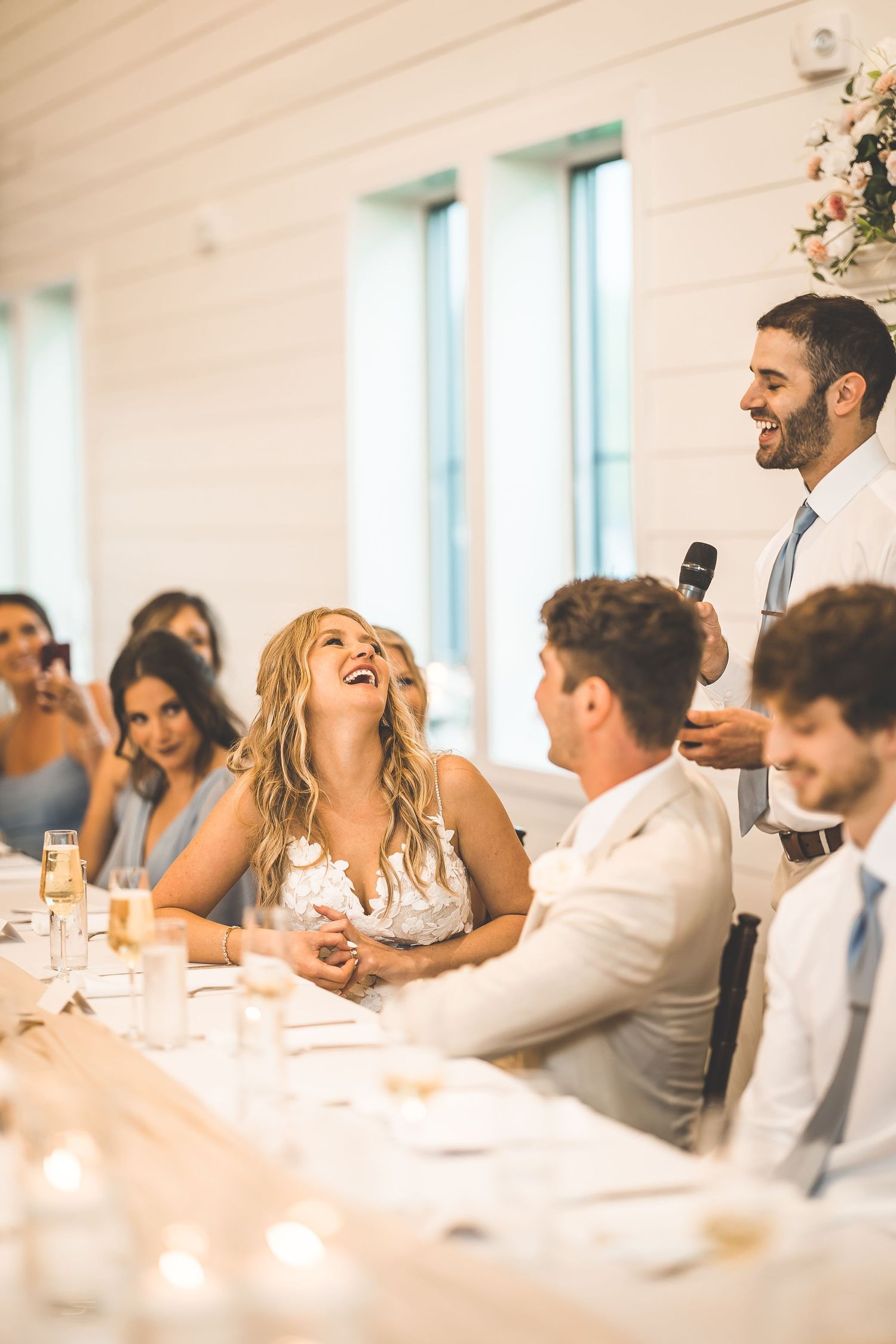 Wedding reception guests enjoying dinner and conversation at elegantly decorated tables.
