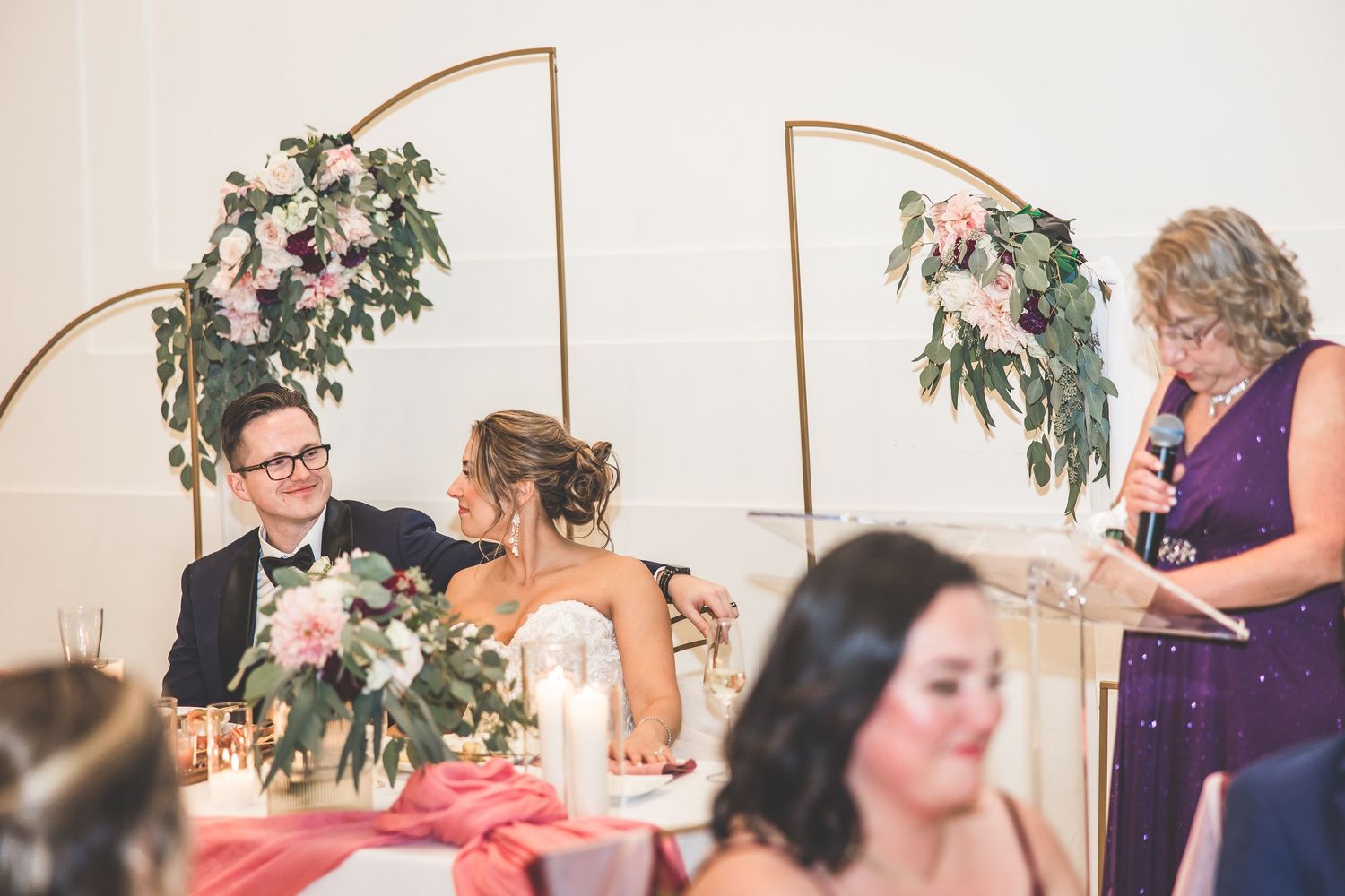 Wedding reception dinner with burgundy bridesmaid dresses and elegant table settings.