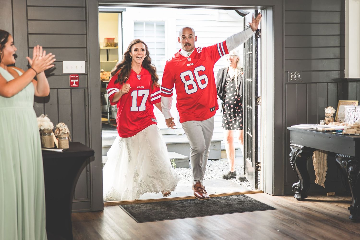 Wedding party celebrating with guests wearing red sports jerseys on the dance floor.