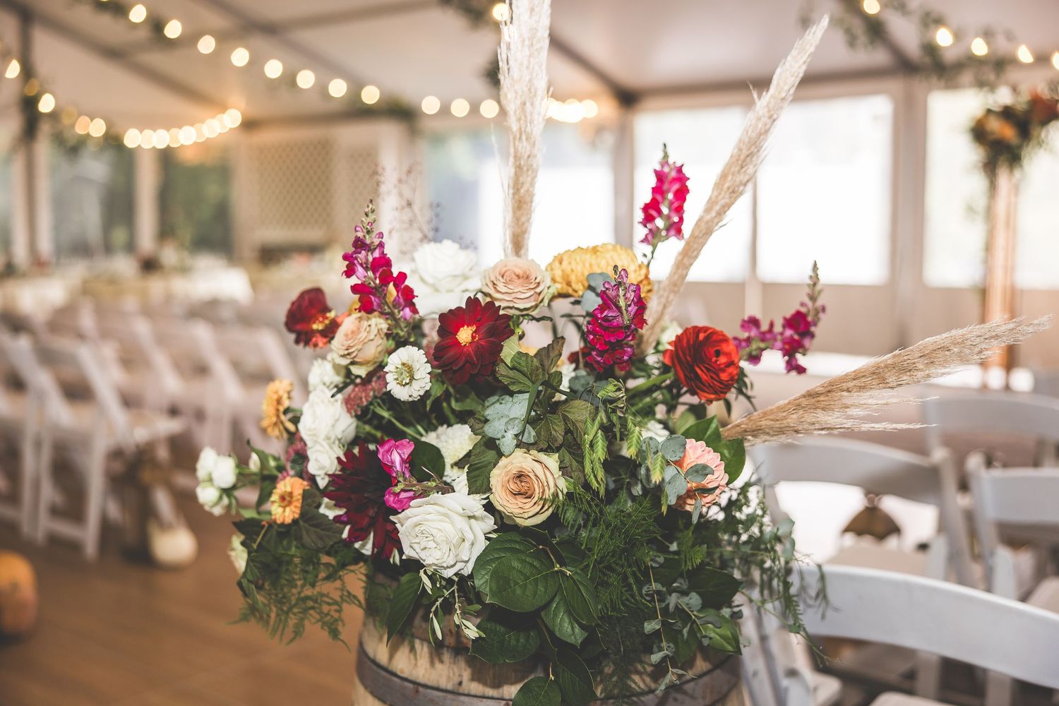 Indoor wedding ceremony space with hanging lights and white folding chairs.