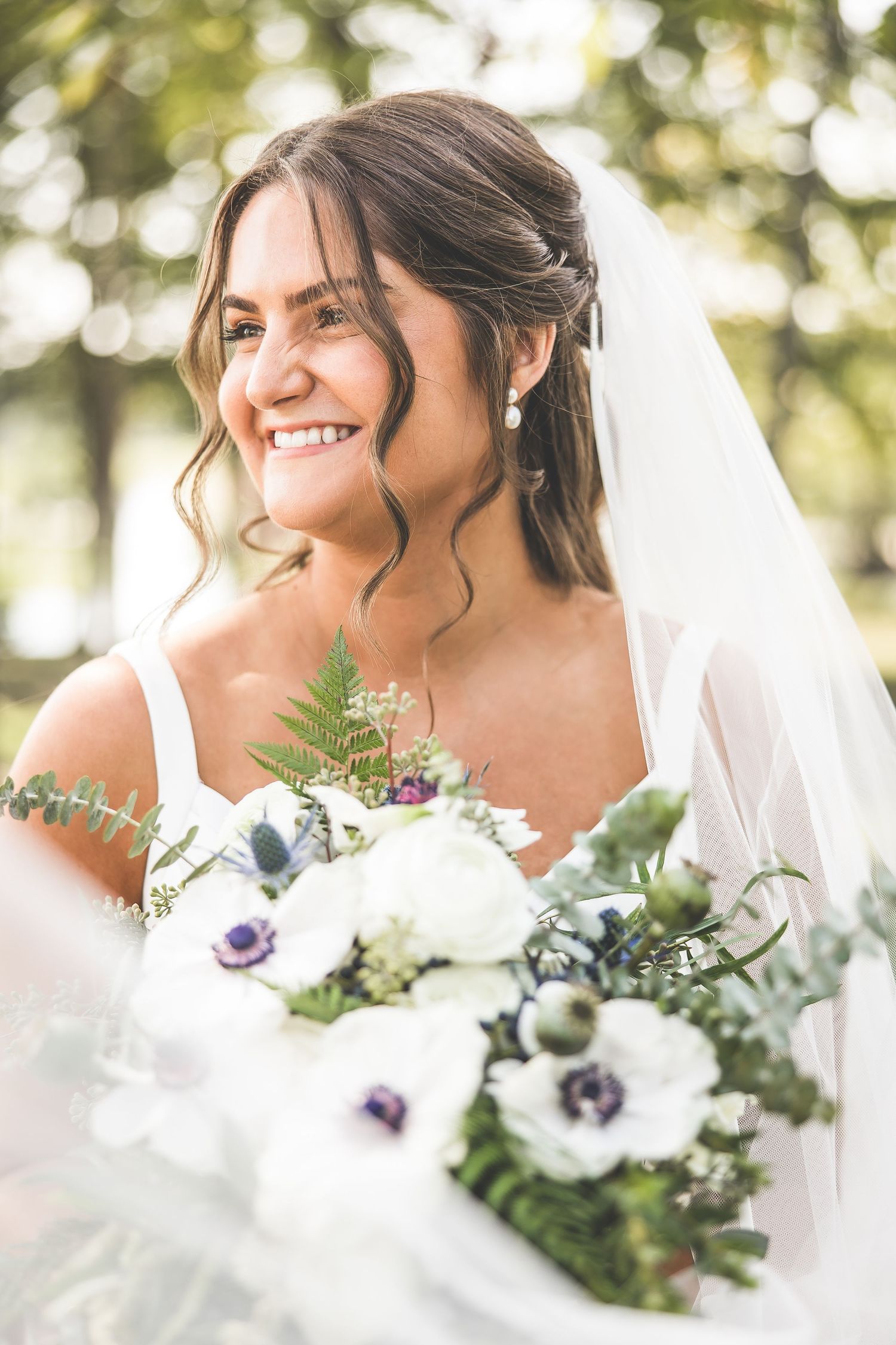 Elegant bridal bouquet features white and purple anemone flowers with delicate greenery.