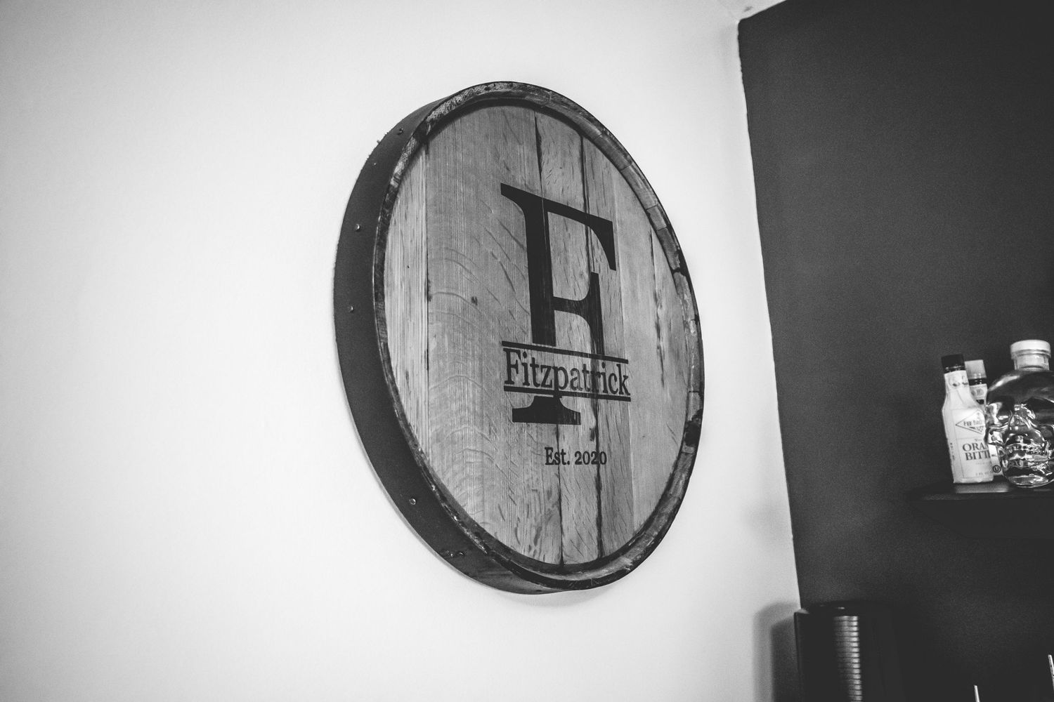 A rustic wooden barrel lid mounted on a wall features a minimalist logo design.