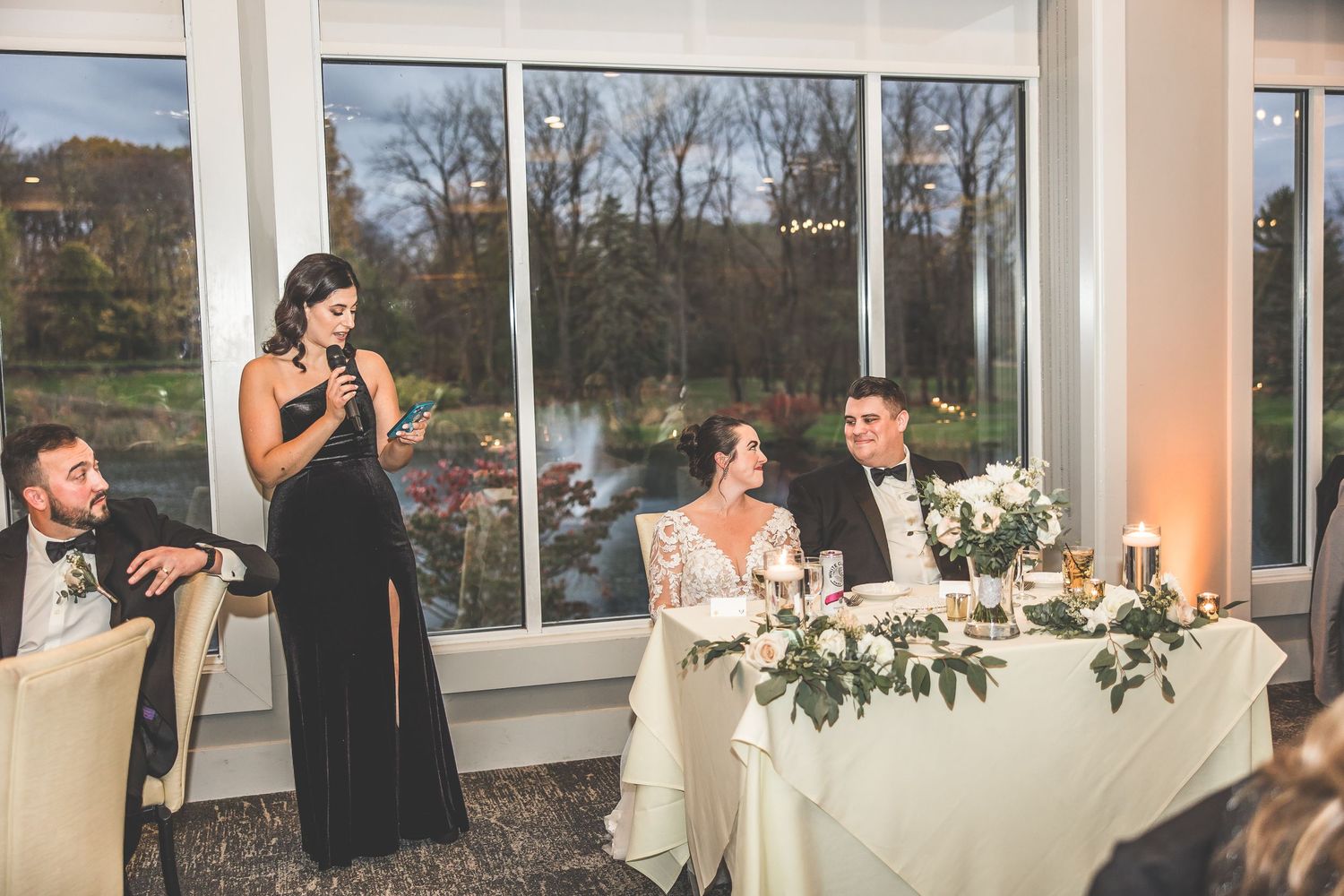Elegant wedding reception venue with large windows and floral table decorations.