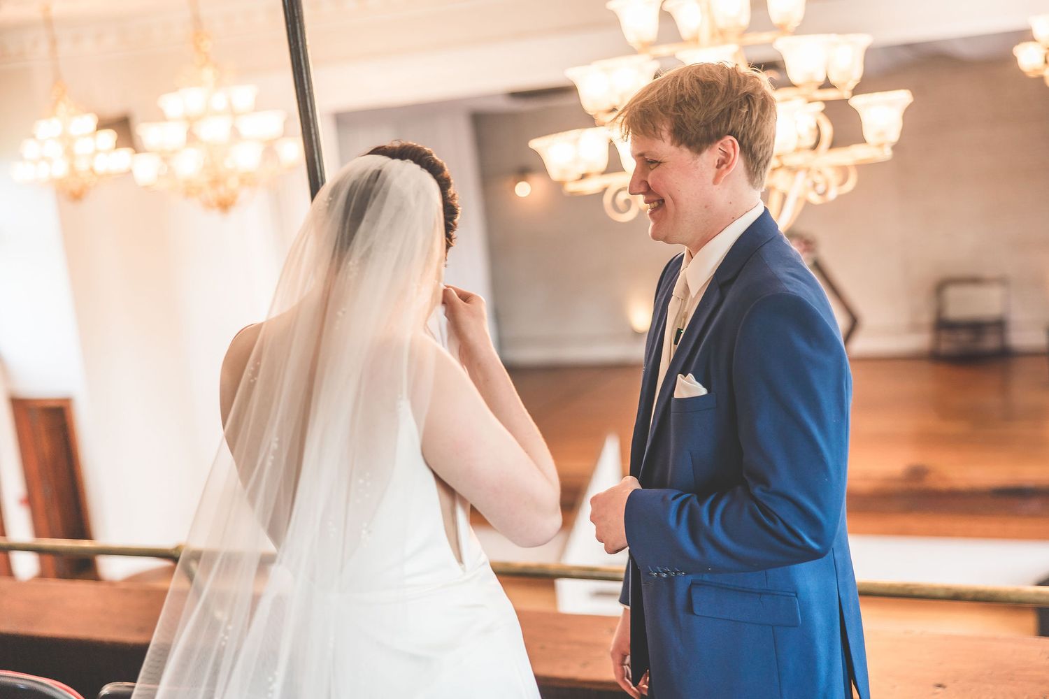 Elegant wedding couple shares a romantic moment in a vintage theater with ornate architectural details.