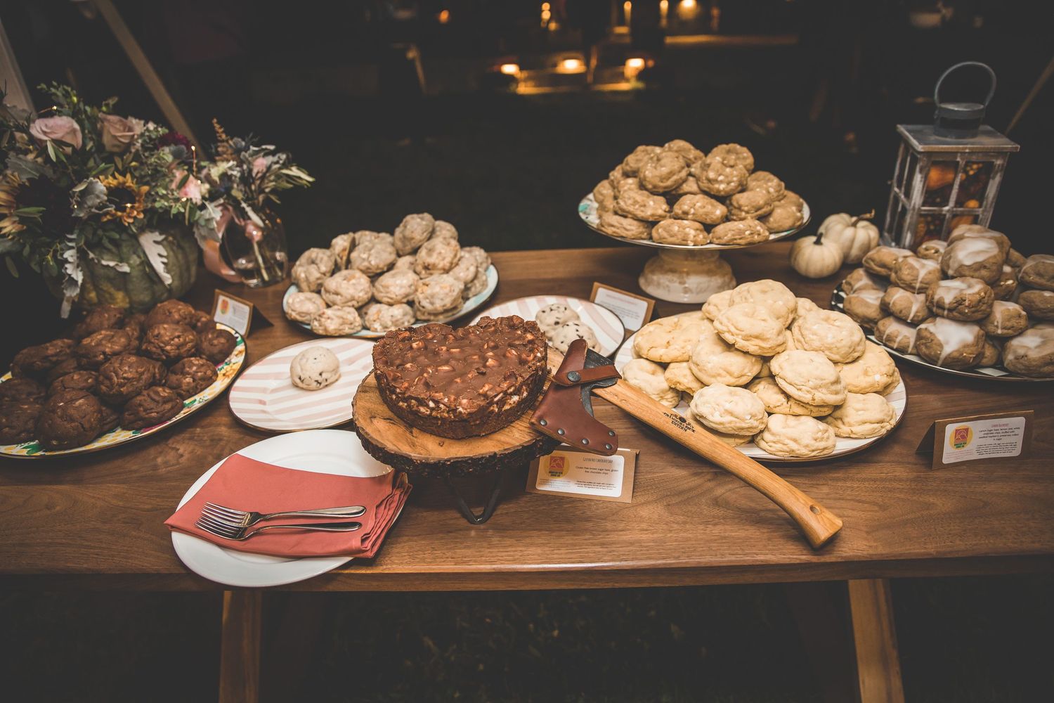 Dessert table at wedding reception displaying various cookies and treats on rustic wooden table.